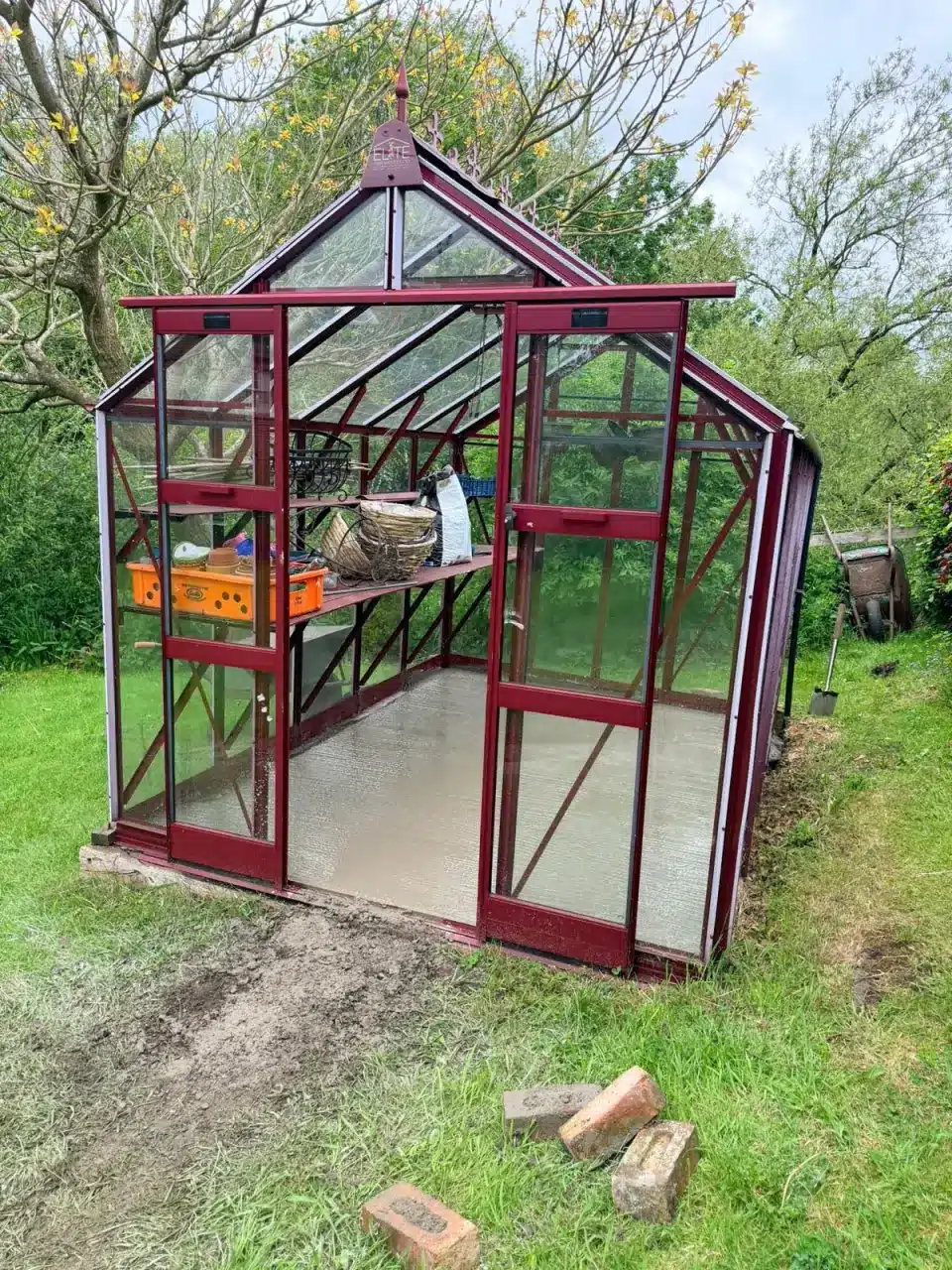 Greenhouse with a freshly laid concrete base in a Mobberley garden