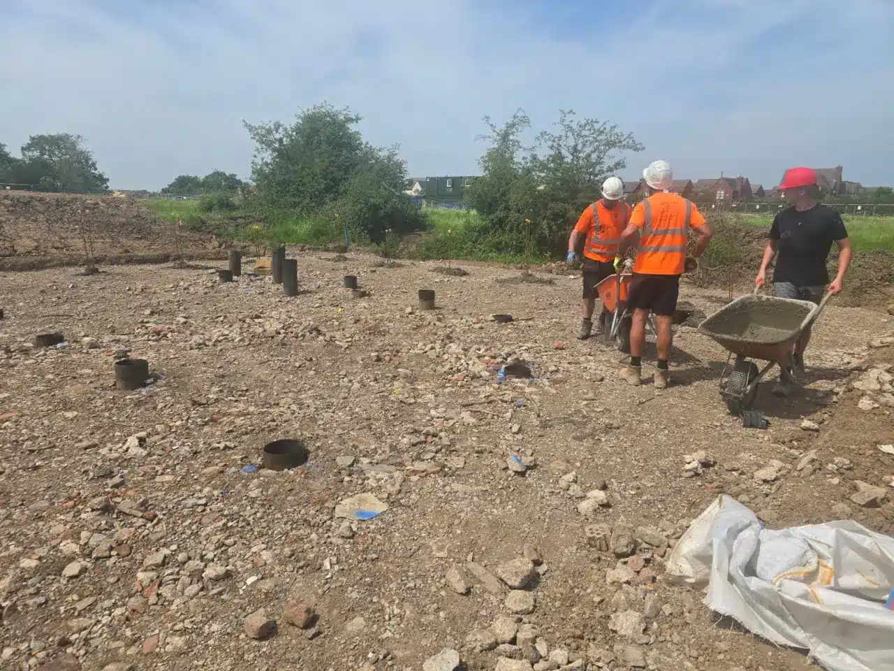 Barrow Mix team barrowing concrete across a foundation plot