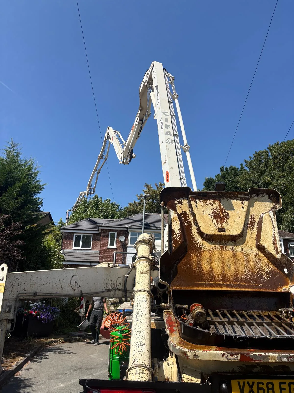 Boom pump arm reaching up and over the houses on a sunny day