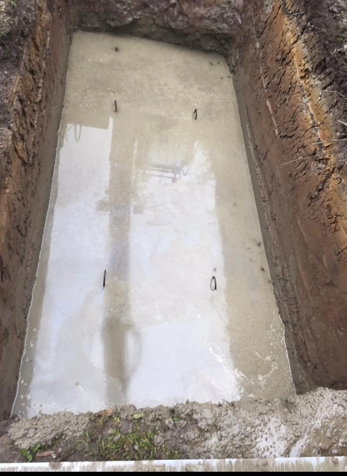 Concrete gas-tank base with four anchor plates cast into the slab to strap the LPG tank down against uplift, Mobberley