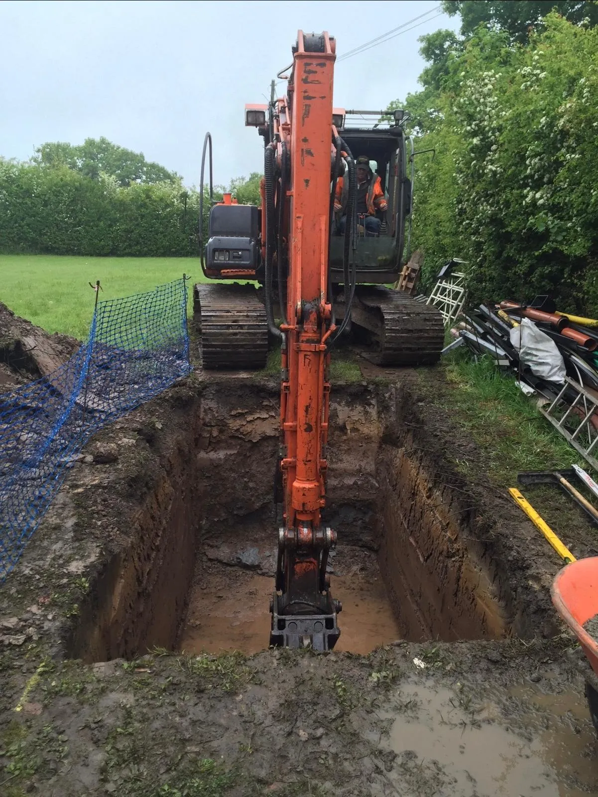 Excavator digging out the pit for a gas-tank anchor base in a Mobberley back garden