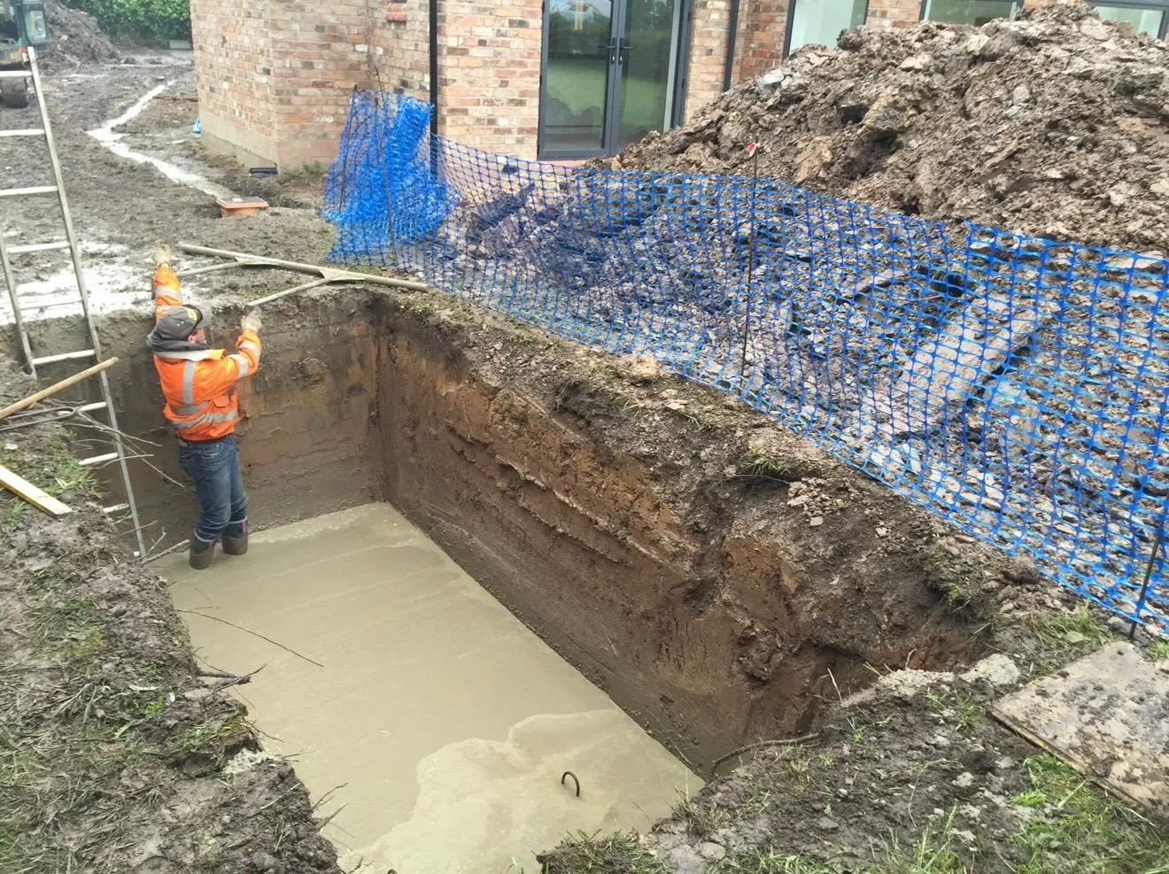 Barrow Mix concrete being placed and finished in the gas-tank base pit at a Mobberley new build