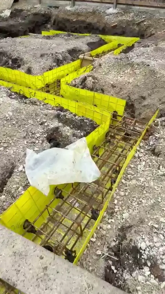 Crew placing pumped concrete into reinforced footings on a piled site in the Oldham area