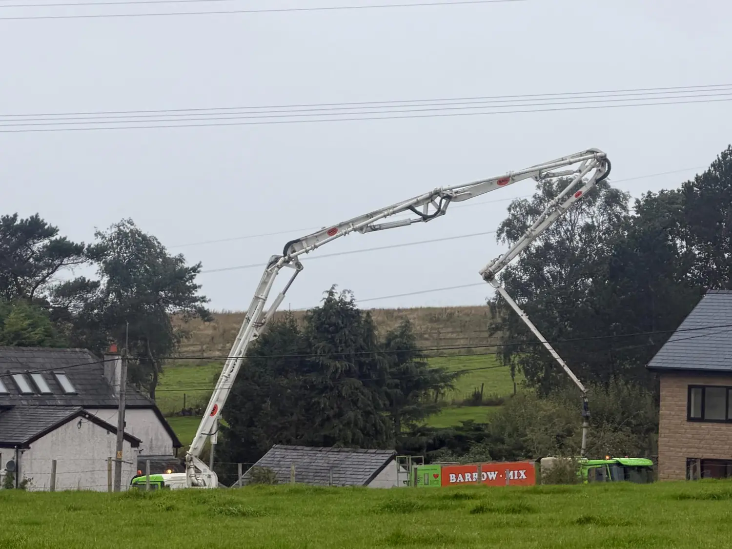 Boom pump reaching over trees and outbuildings to a new-build site near Oldham, fed by a Barrow Mix wagon