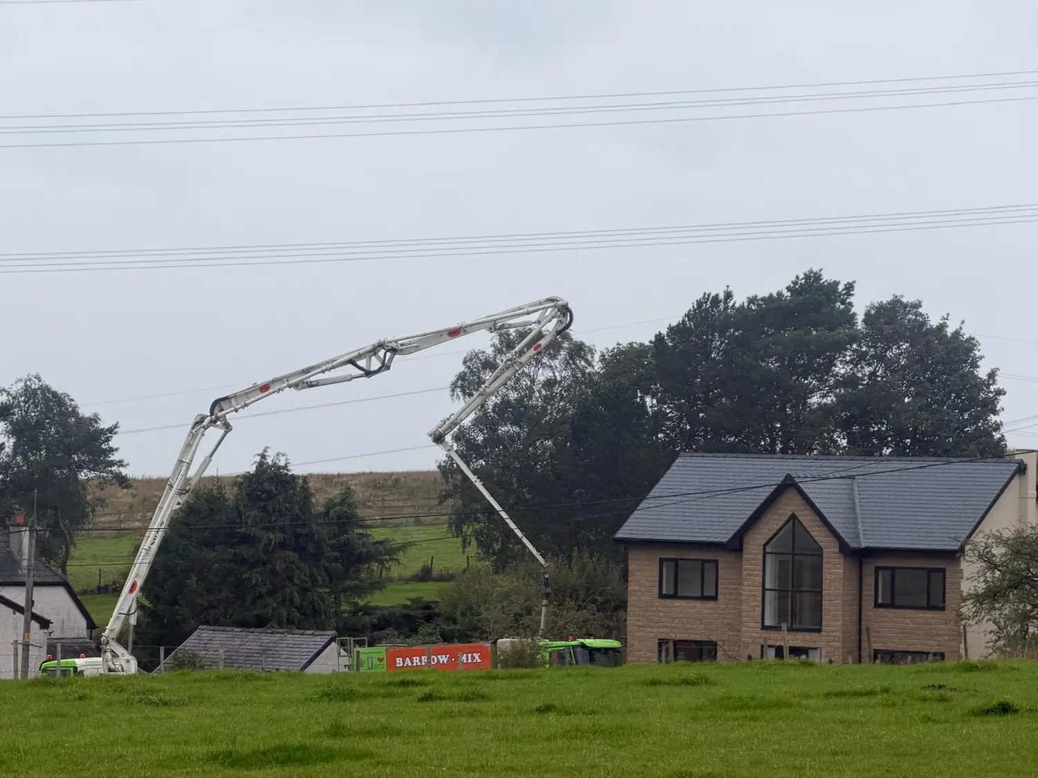 Boom pump over the footings beside a new-build house in the Oldham area