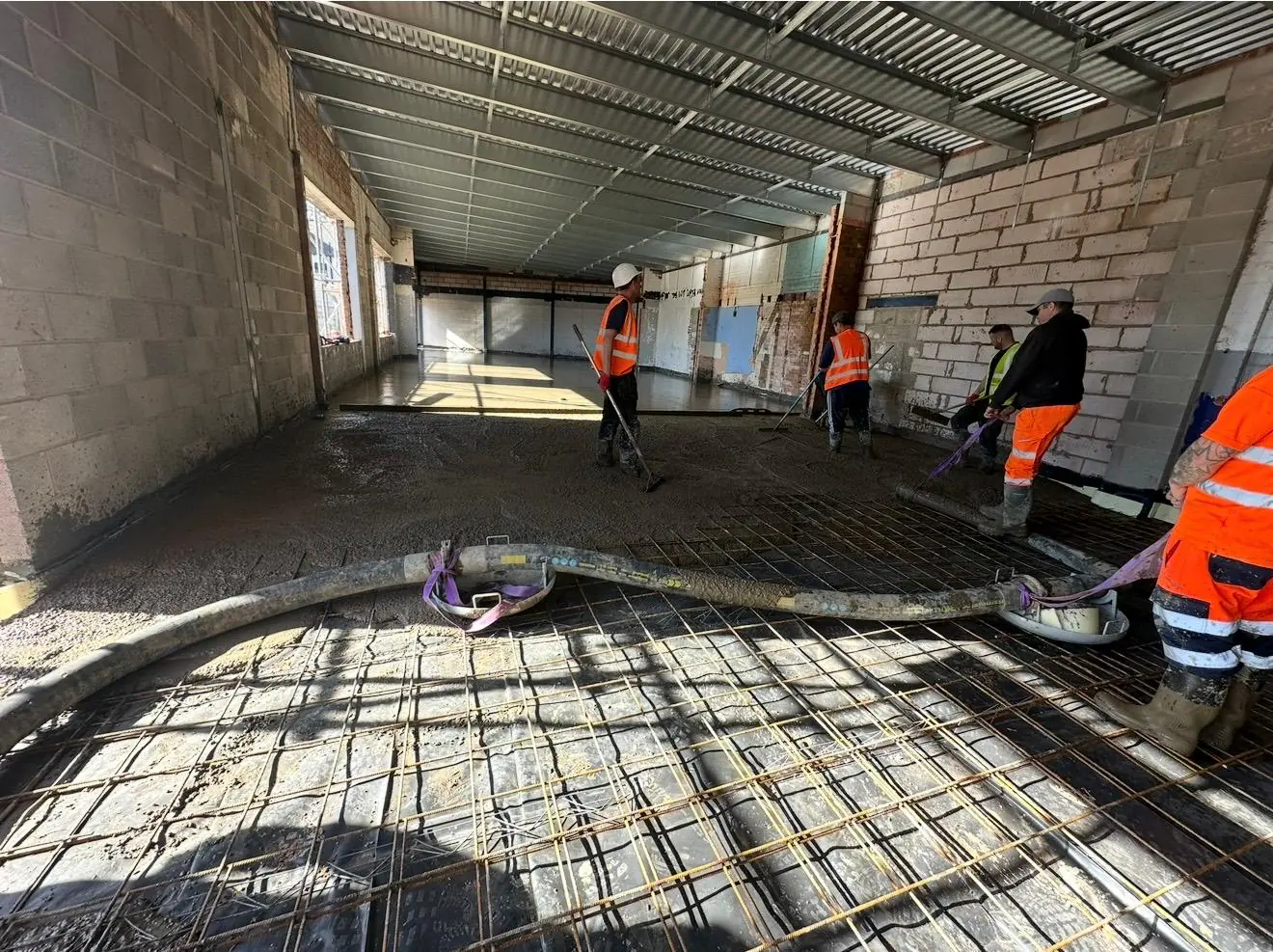 Pump line laid over steel mesh as the crew places concrete inside the Tesco Express in Cadishead